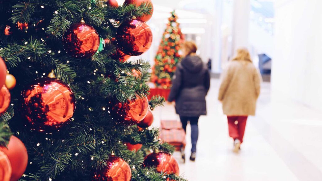 Karácsonyi bevásárlás a karácsonyfák között sétáló nőkkel